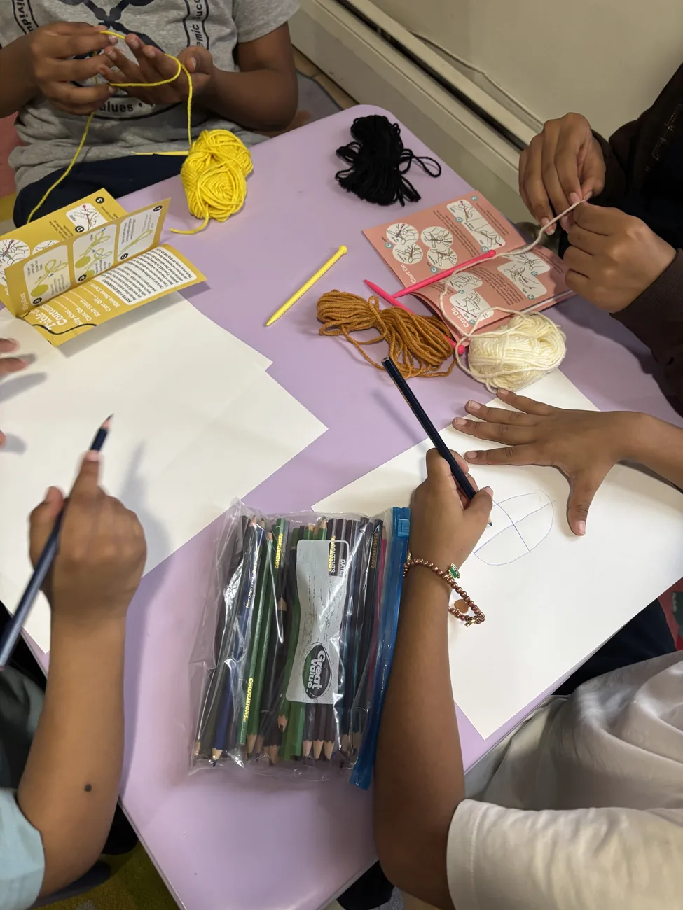 Children working together on a yarn and drawing activity