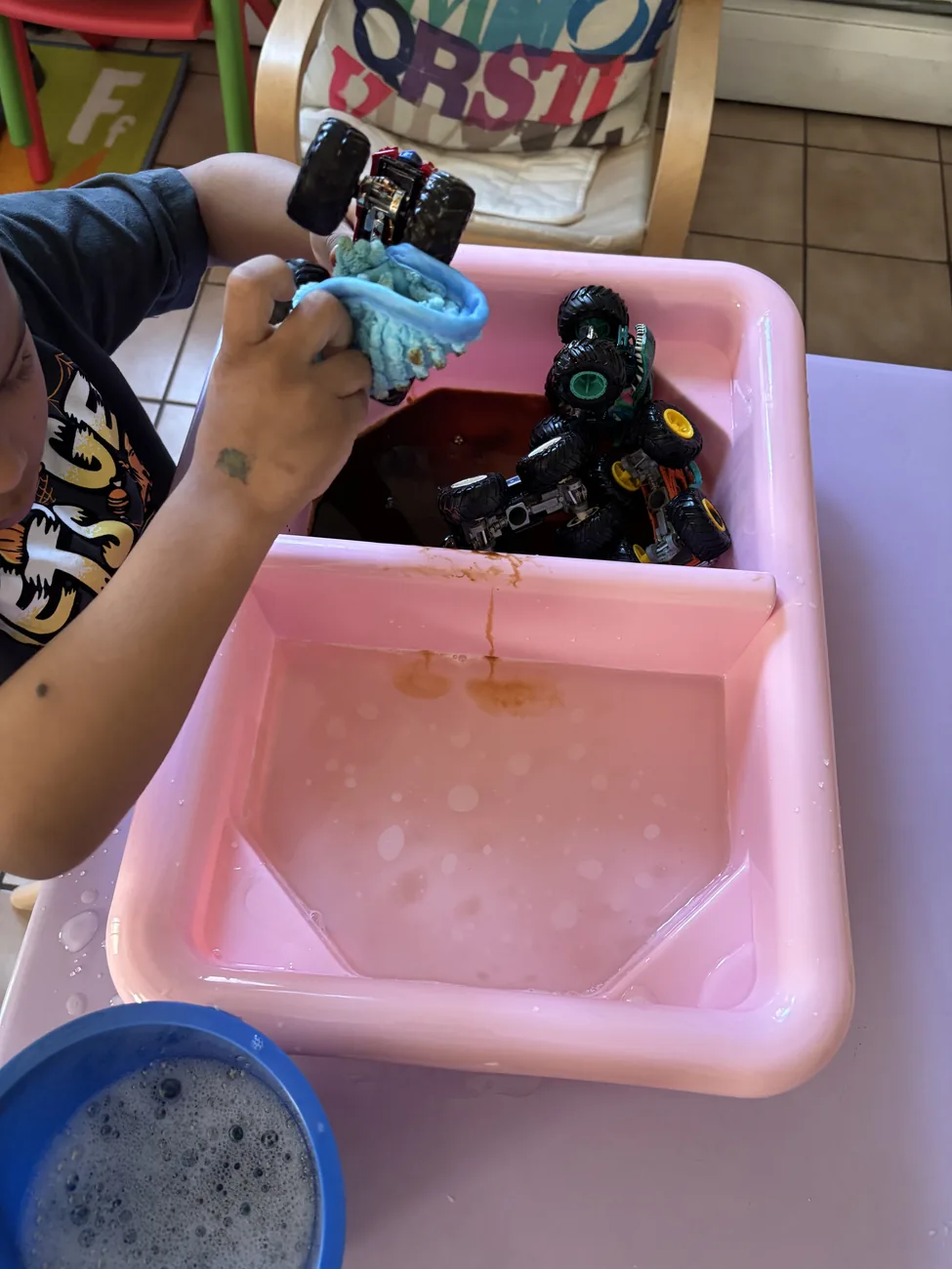 A child washing toy trucks during a supervised sensory activity